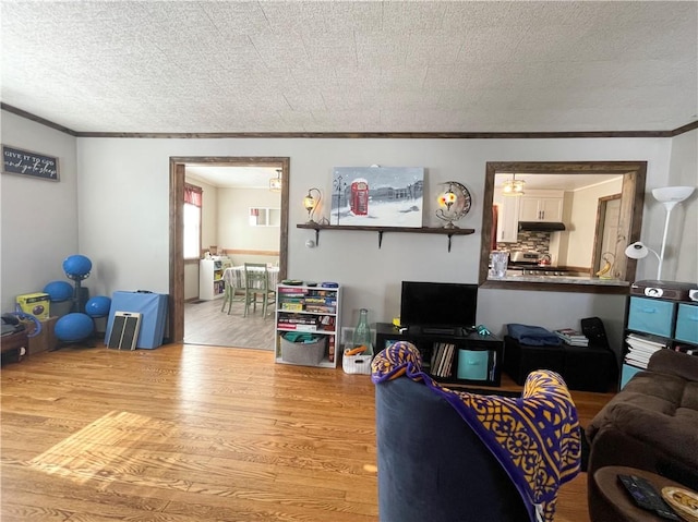 living room featuring a textured ceiling, ornamental molding, and light hardwood / wood-style floors