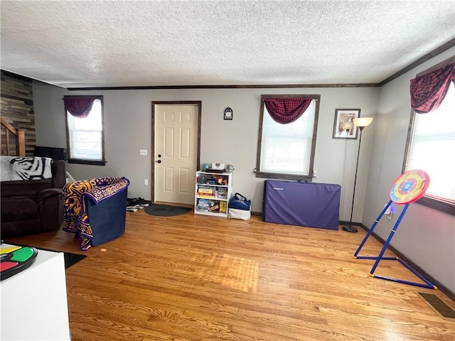 living room with crown molding, wood-type flooring, and a textured ceiling