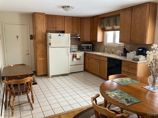 1612 Copperfield St, Utica, NY 13501 - kitchen featuring white appliances, brown cabinetry, under cabinet range hood, light countertops, and a sink