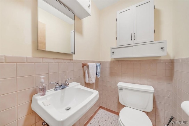 bathroom featuring sink, toilet, and tile walls