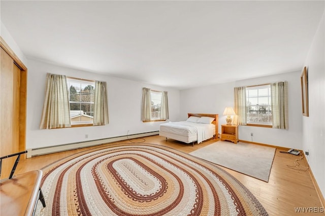 bedroom featuring a baseboard heating unit, a closet, and light hardwood / wood-style floors