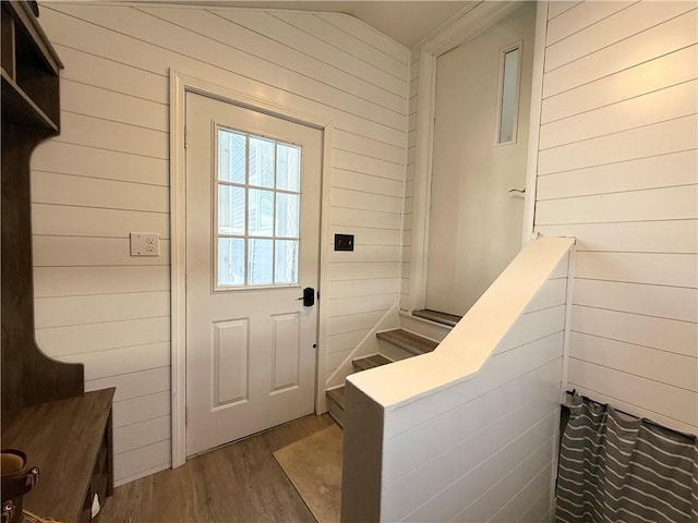 entryway with hardwood / wood-style flooring, wood walls, and lofted ceiling