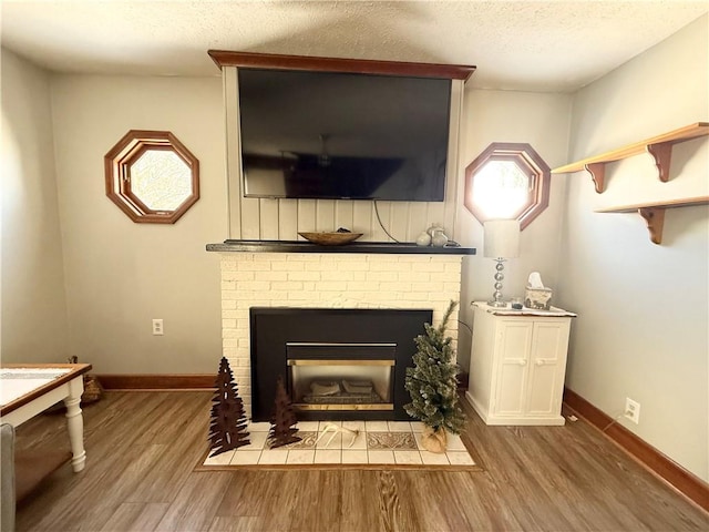 interior space featuring a brick fireplace, hardwood / wood-style flooring, and a textured ceiling