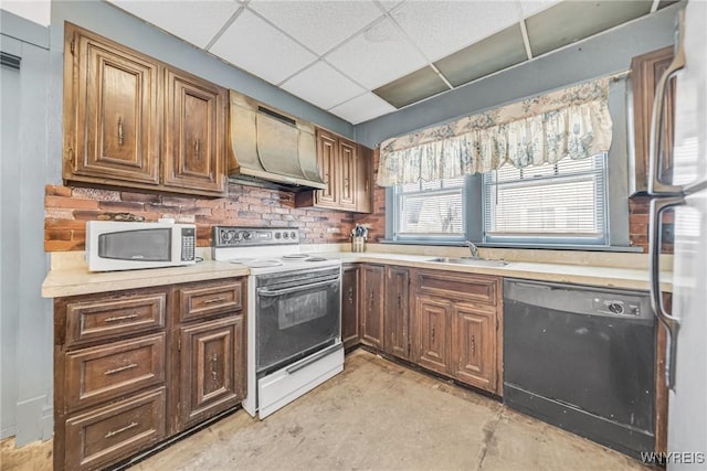 kitchen with sink, white appliances, wall chimney exhaust hood, and a drop ceiling