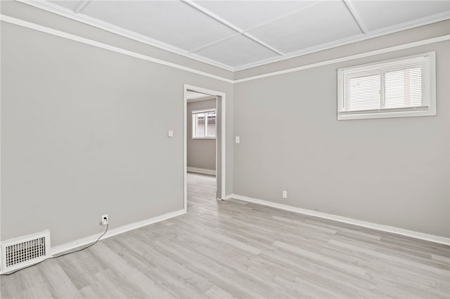 empty room featuring light wood-style floors, baseboards, visible vents, and crown molding