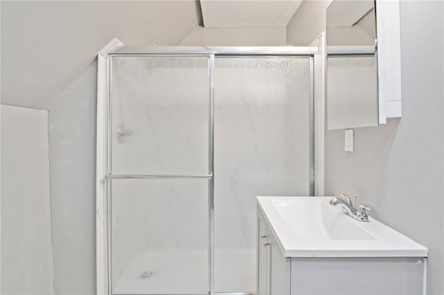 bathroom featuring a shower with door, vaulted ceiling, and vanity