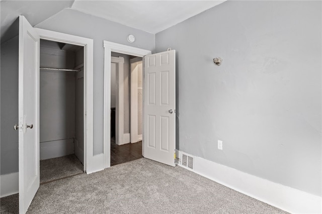 unfurnished bedroom featuring lofted ceiling, a closet, carpet, and visible vents