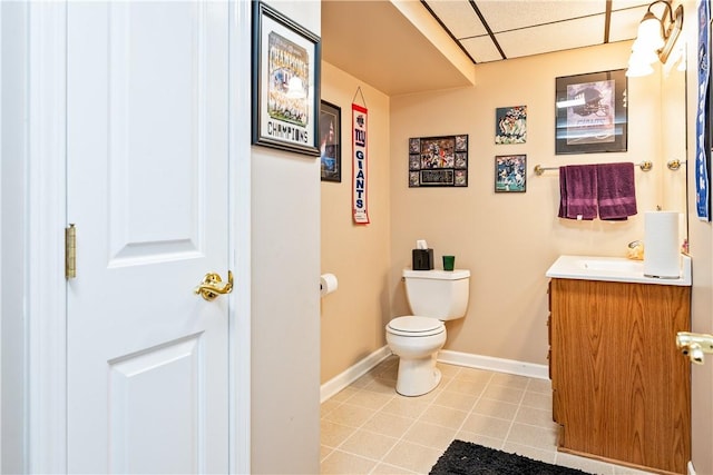 bathroom with toilet, a paneled ceiling, vanity, and tile patterned flooring