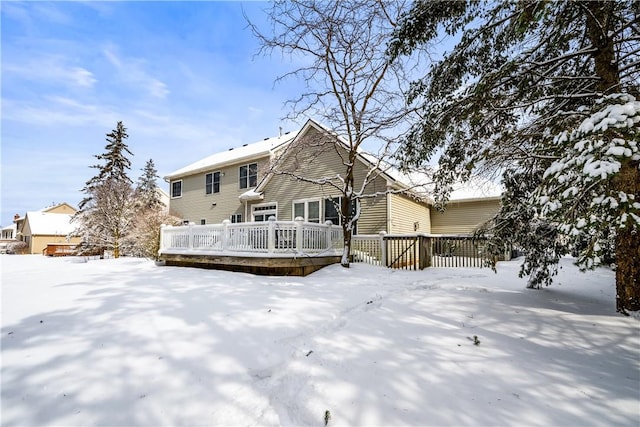 snow covered back of property featuring a wooden deck