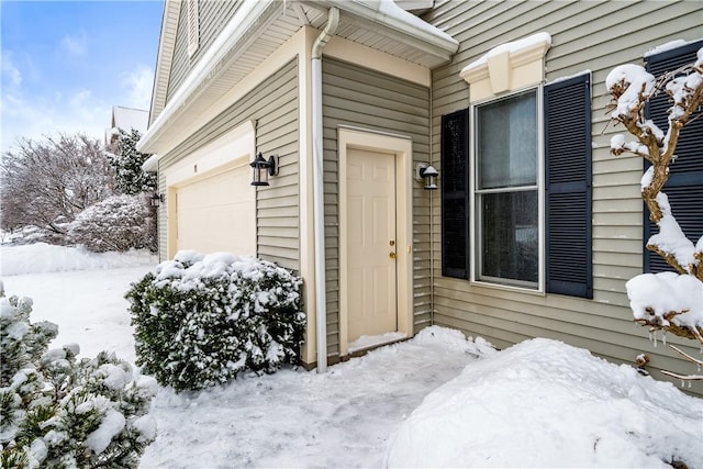 snow covered property entrance with a garage