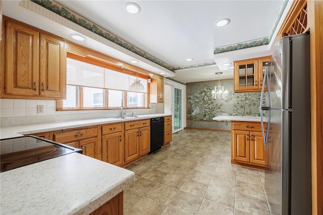 kitchen featuring sink, a notable chandelier, pendant lighting, dishwasher, and stainless steel refrigerator