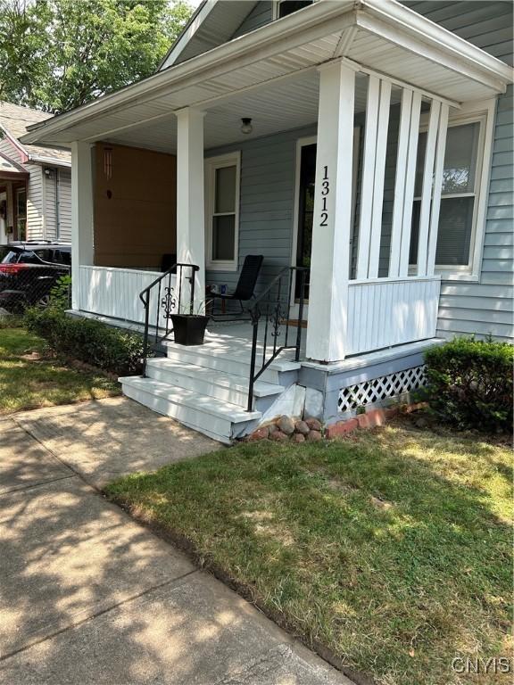 entrance to property featuring covered porch and a yard