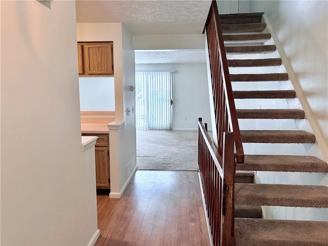 stairway with wood-type flooring and a textured ceiling