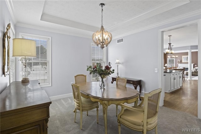 dining space featuring a raised ceiling, carpet, a chandelier, and crown molding