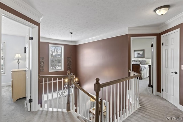 hallway with light carpet, crown molding, and a textured ceiling