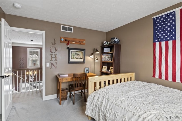 carpeted bedroom featuring a textured ceiling and a chandelier