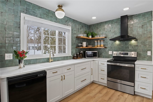 kitchen with white cabinetry, stainless steel appliances, light hardwood / wood-style flooring, sink, and wall chimney range hood