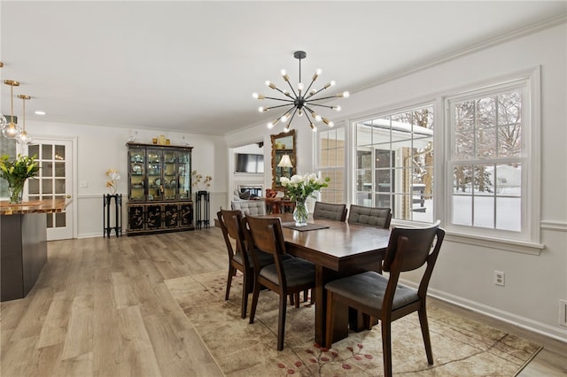 dining space with ornamental molding, light hardwood / wood-style floors, and a chandelier