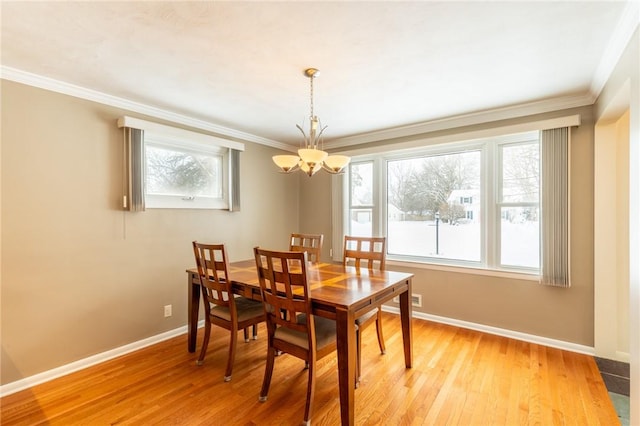 dining area featuring crown molding, an inviting chandelier, and light hardwood / wood-style floors