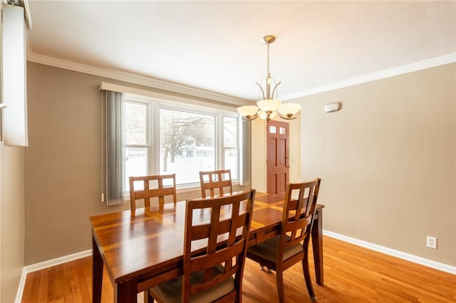 dining room with an inviting chandelier, hardwood / wood-style flooring, and ornamental molding