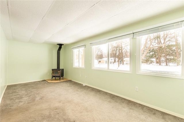 unfurnished living room featuring carpet flooring, a wood stove, and a textured ceiling