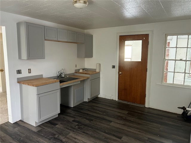 kitchen with sink, wooden counters, gray cabinetry, and dark wood-type flooring