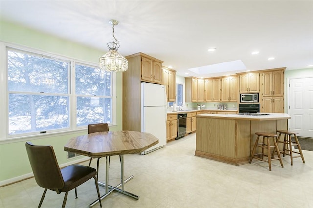 kitchen with a center island, light countertops, pendant lighting, stainless steel microwave, and freestanding refrigerator