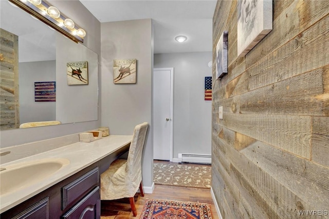 bathroom with wood-type flooring, vanity, and a baseboard radiator