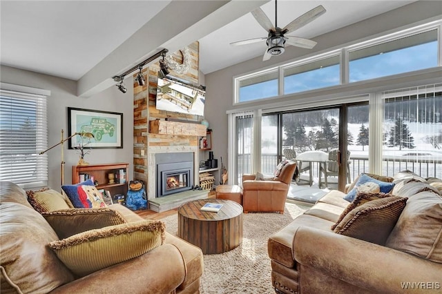 living room with beam ceiling, ceiling fan, and a large fireplace