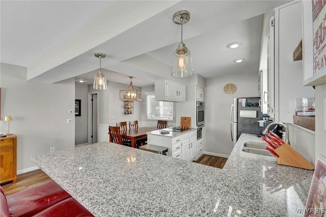 kitchen with white cabinets, sink, kitchen peninsula, and light hardwood / wood-style flooring