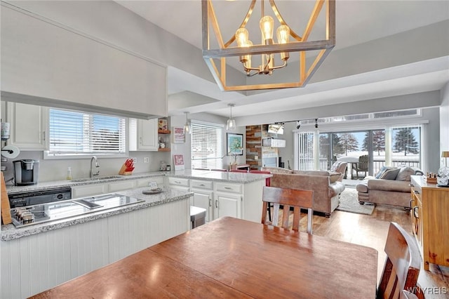 kitchen with decorative light fixtures, light stone countertops, sink, a healthy amount of sunlight, and white cabinets