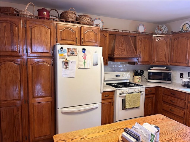 kitchen featuring decorative backsplash, white appliances, and custom range hood