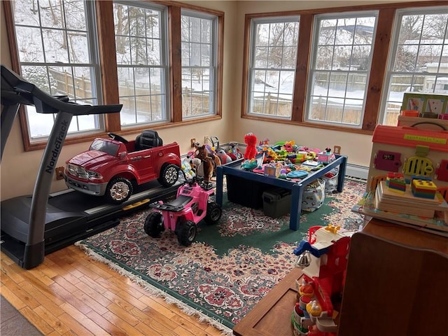 game room featuring a baseboard heating unit and hardwood / wood-style floors