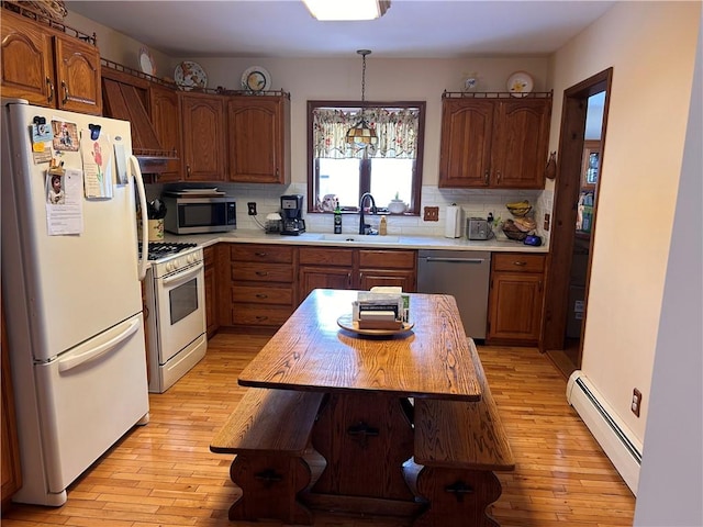 kitchen featuring light wood-type flooring, stainless steel appliances, a baseboard heating unit, sink, and pendant lighting