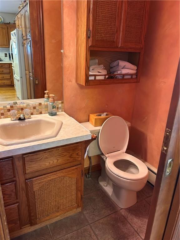 bathroom with tile patterned floors, toilet, vanity, and decorative backsplash