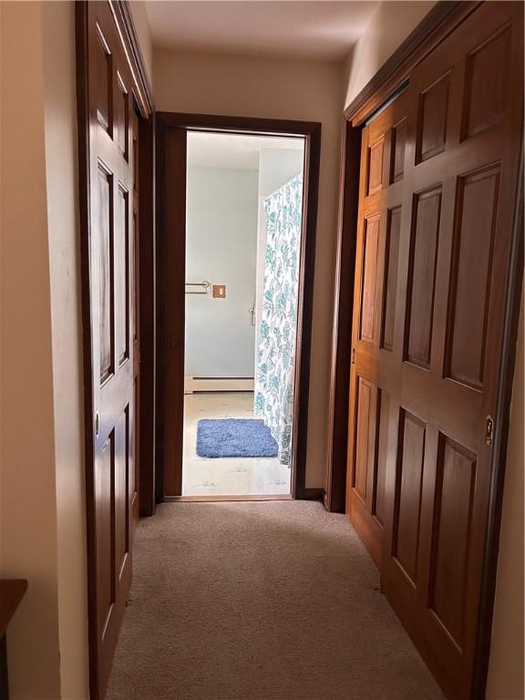 hallway featuring light carpet and a baseboard radiator