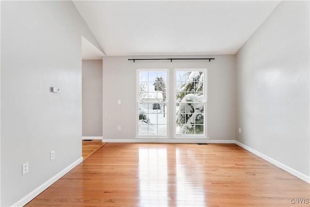 unfurnished room with visible vents, light wood-style flooring, and baseboards