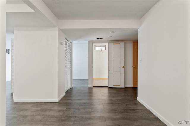 unfurnished room featuring dark wood-style flooring, visible vents, and baseboards