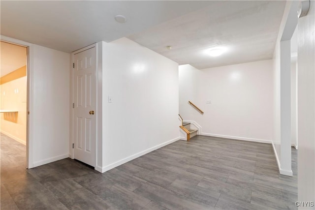 below grade area featuring baseboards, stairway, and wood finished floors