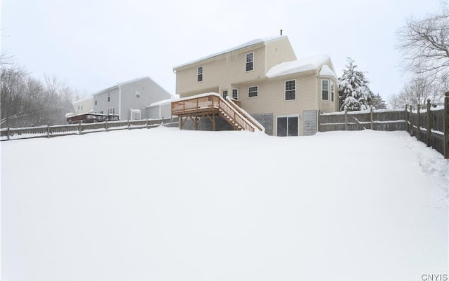 snow covered property featuring fence, stairway, and a wooden deck