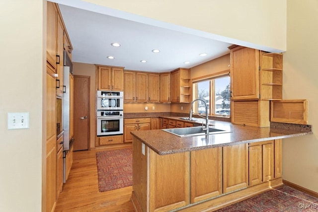 kitchen with double oven, light hardwood / wood-style flooring, sink, and kitchen peninsula