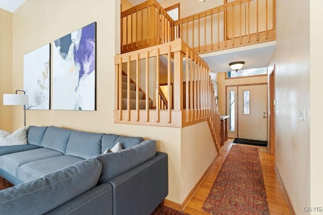 living room featuring light wood-type flooring and a towering ceiling