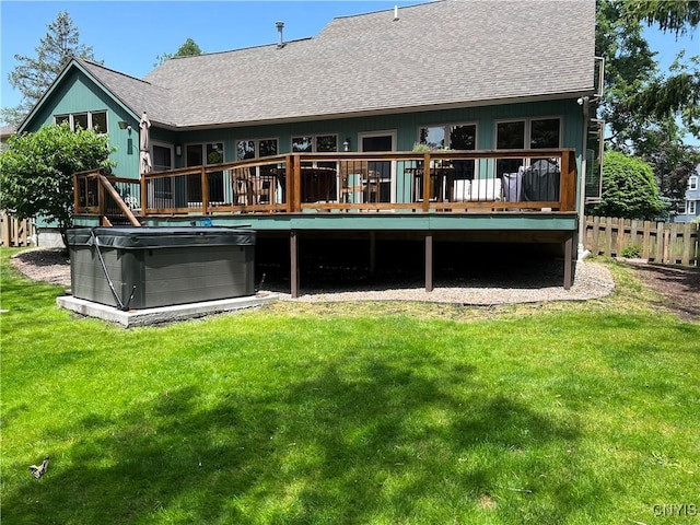 rear view of house with a lawn, a wooden deck, and a hot tub