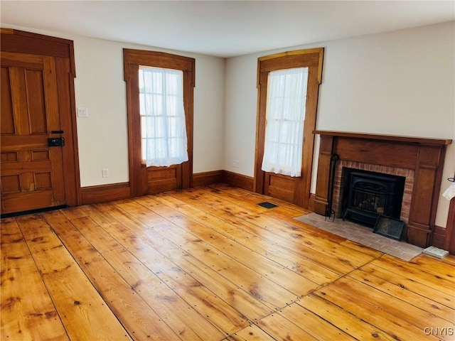 unfurnished living room with a brick fireplace and light hardwood / wood-style flooring