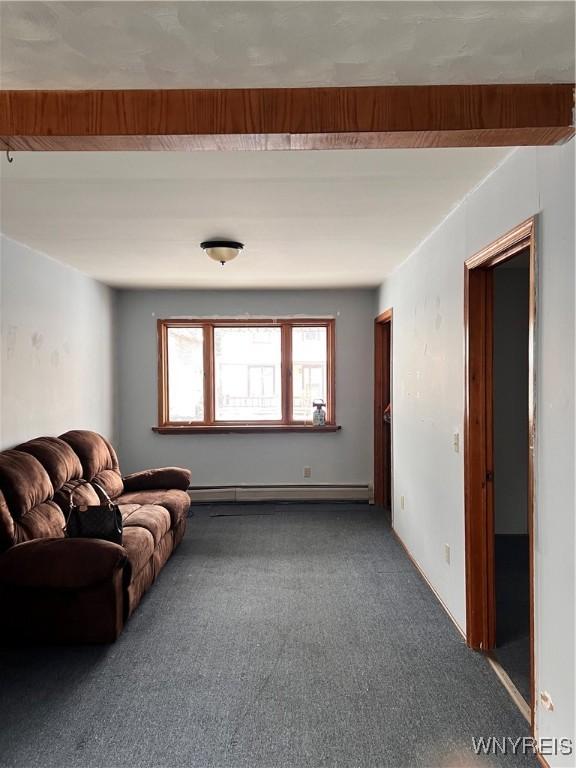 unfurnished living room featuring a baseboard heating unit, beam ceiling, and carpet flooring