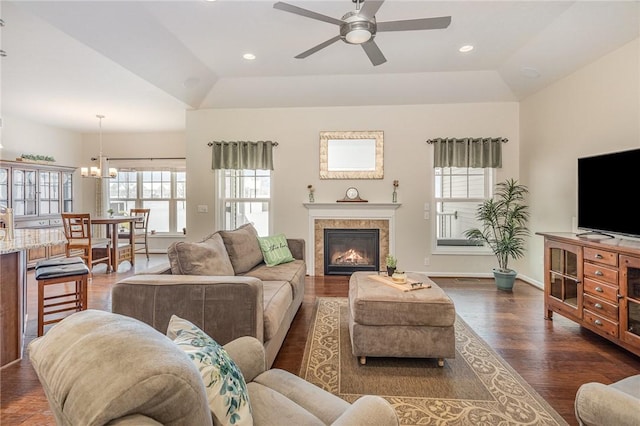 living room with a tray ceiling, dark hardwood / wood-style flooring, and ceiling fan with notable chandelier