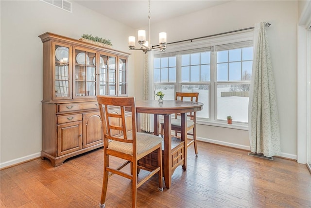 dining space with light wood-type flooring and an inviting chandelier