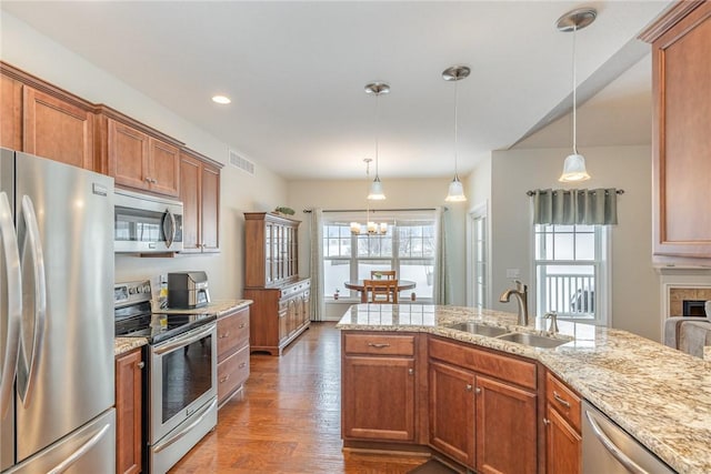 kitchen featuring wood-type flooring, appliances with stainless steel finishes, sink, and decorative light fixtures