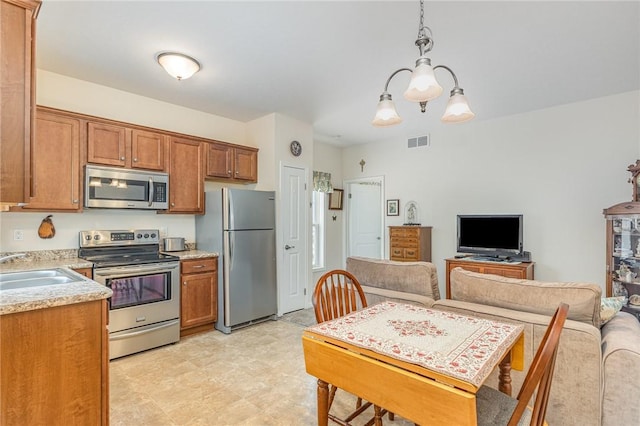 kitchen with appliances with stainless steel finishes, decorative light fixtures, sink, and a notable chandelier