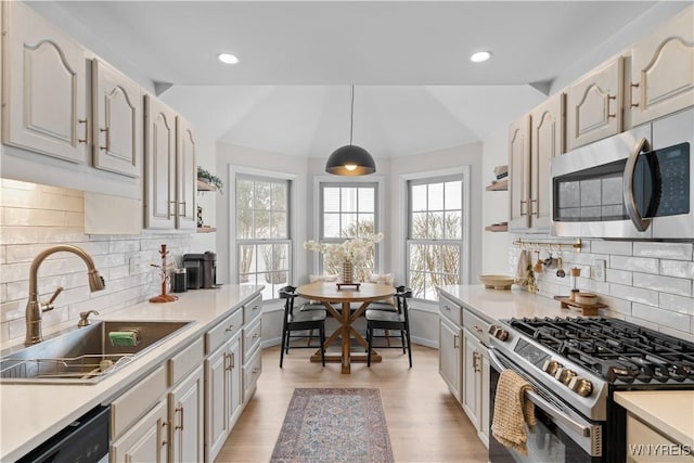 kitchen featuring decorative light fixtures, vaulted ceiling, stainless steel appliances, and sink